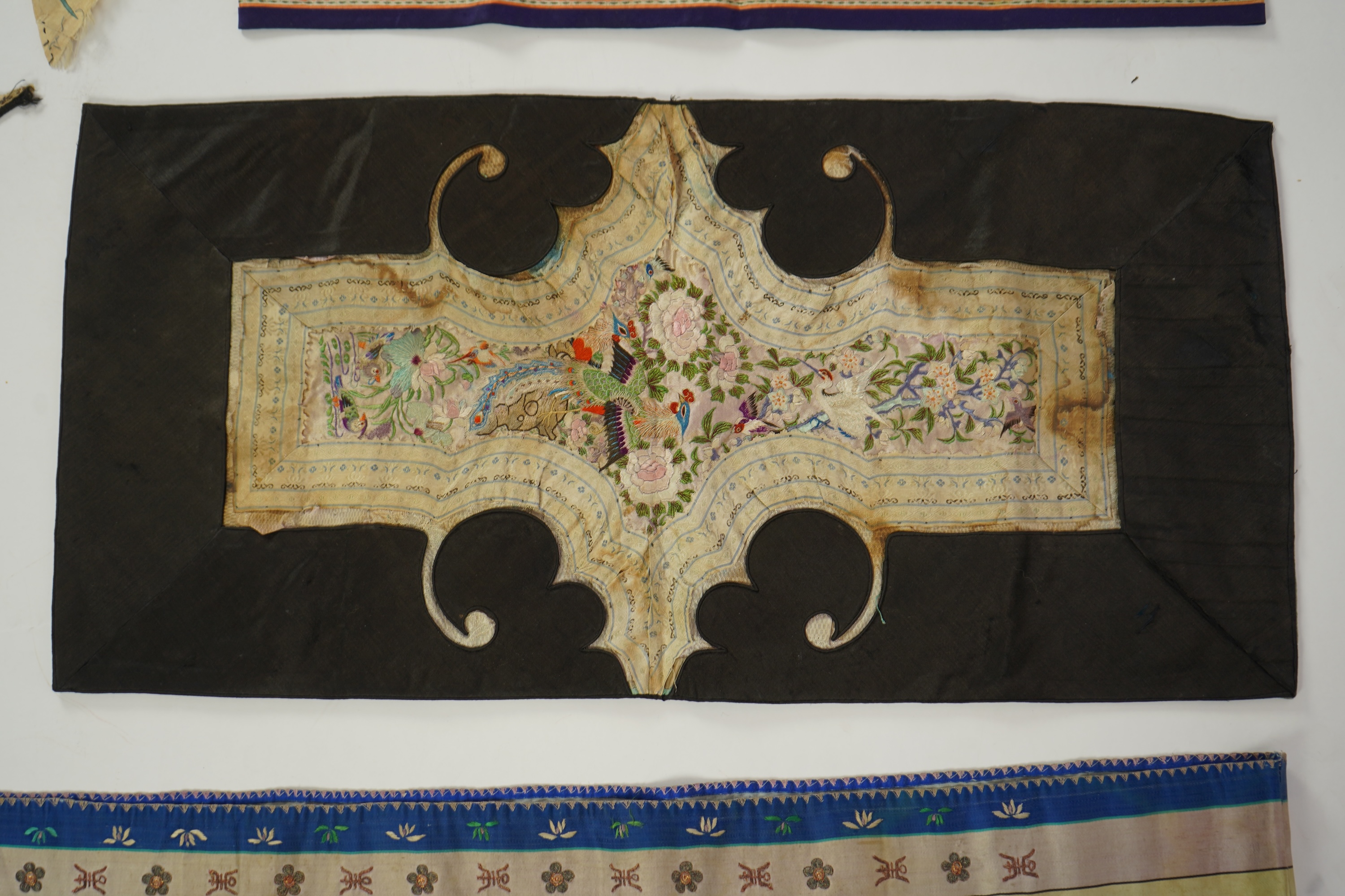 A Chinese embroidered silk panel of uncut robe borders, eleven similar sleeve panels and two other items, late Qing dynasty
